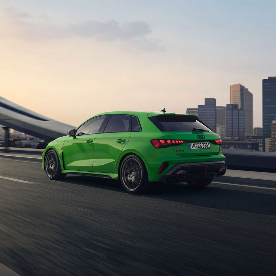 Bright green Audi car driving on a city bridge at dusk
